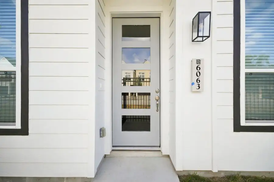 Modern front entry featuring a contemporary glass-panel door, clean architectural details, and exterior lighting.