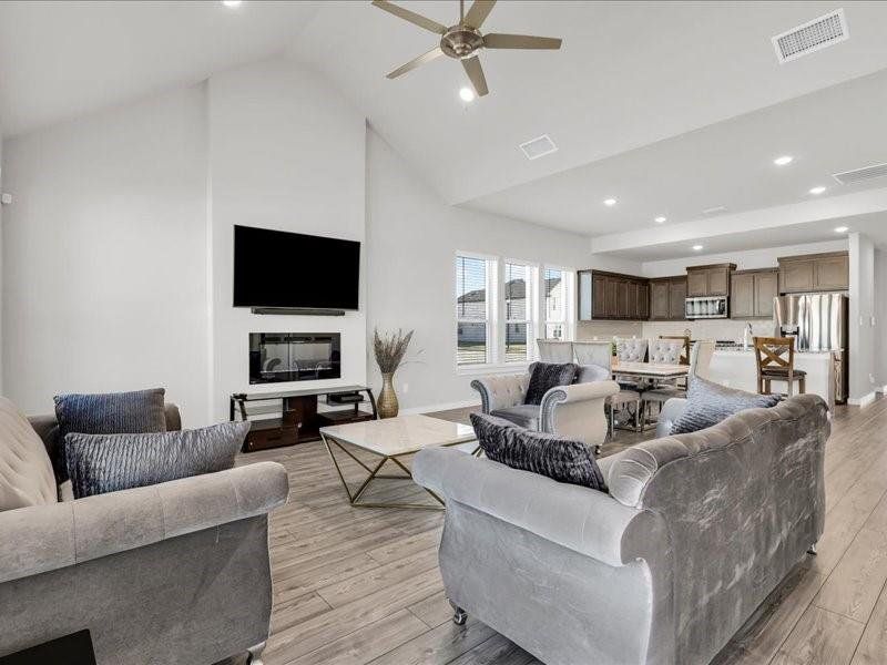 Living room with ceiling fan, light hardwood / wood-style flooring, and high vaulted ceiling