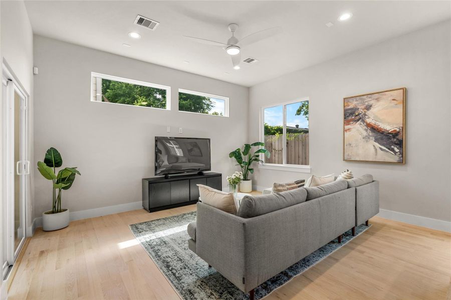 Bright & inviting living room with clerestory windows, a modern ceiling fan & large sliding doors that open to the covered patio for effortless indoor-outdoor living.