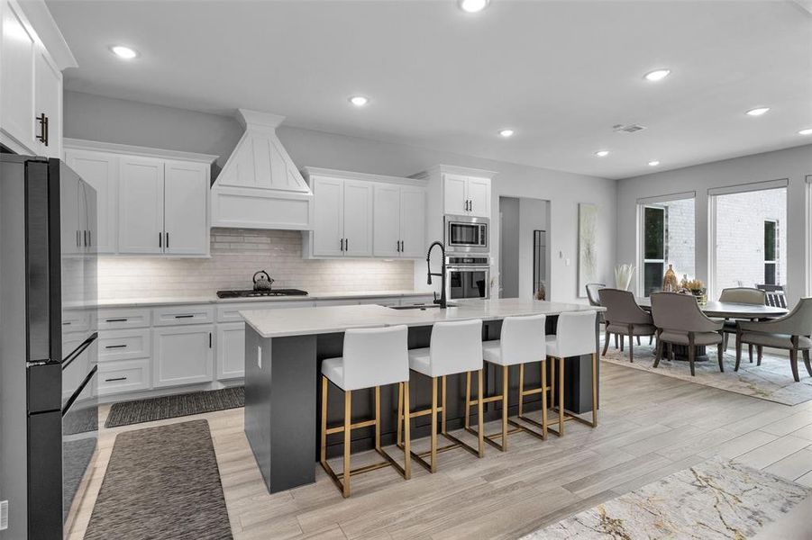 Stainless appliances and sink, modern hood.