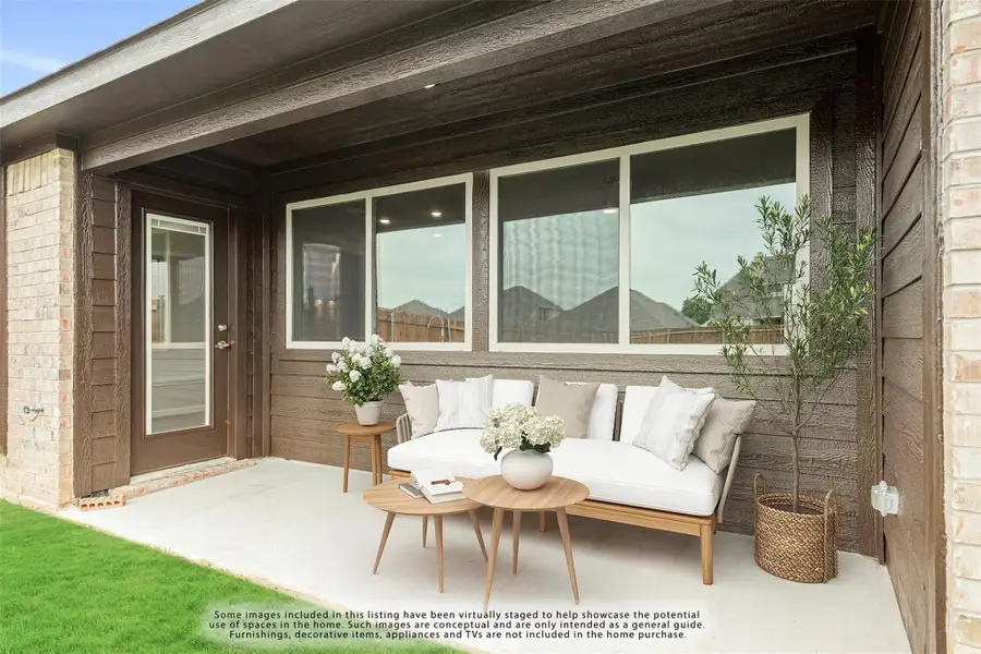 Covered back patio with outdoor sofa, wood coffee table, and large windows on dark siding exterior.