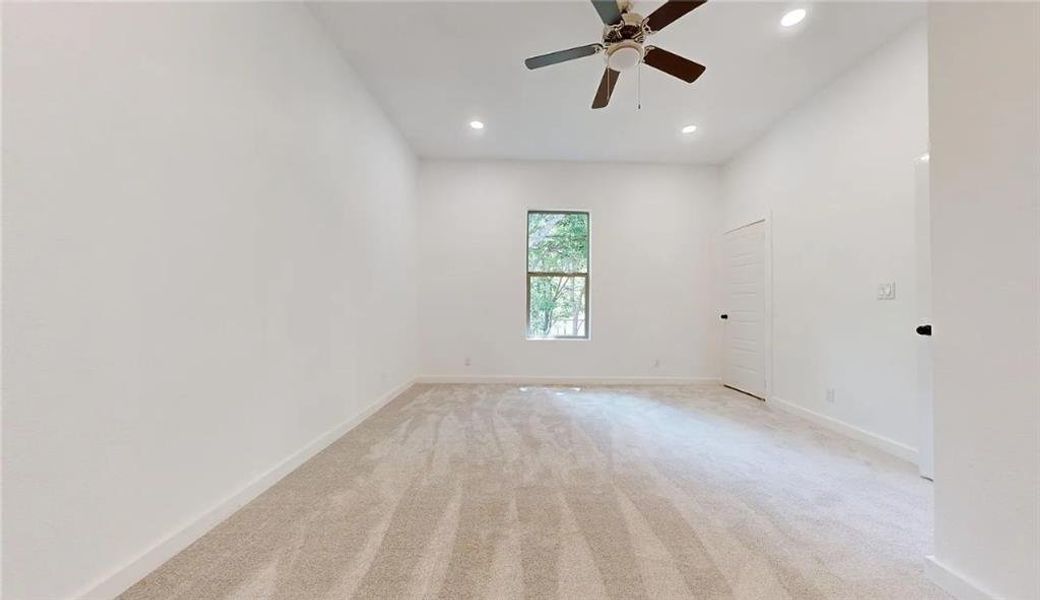 Spacious room featuring neutral carpeting, a single window, recessed lighting, and a ceiling fan