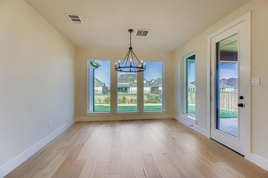 Unfurnished dining area featuring light wood-type flooring and a chandelier