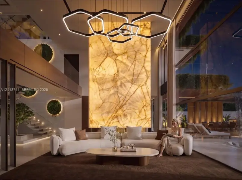 Double-height living area featuring a floor-to-ceiling backlit stone accent wall, multi-tiered geometric pendant lighting, full-height glass walls, and a glass-paneled staircase