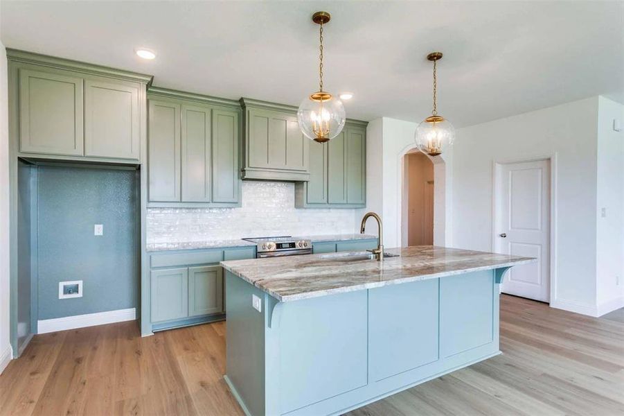 Kitchen featuring arched walkways, stainless steel electric stove, light wood-style floors, light stone counters, and recessed lighting Kitchen featuring arched walkways, stainless steel electric stove, light wood-style floors, light stone counters, and recessed lighting