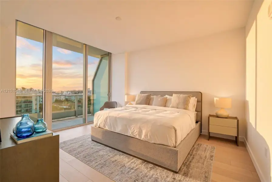 Floor-to-ceiling glass wall with access to an exterior balcony, light-toned wood-finish flooring, and recessed ceiling lighting