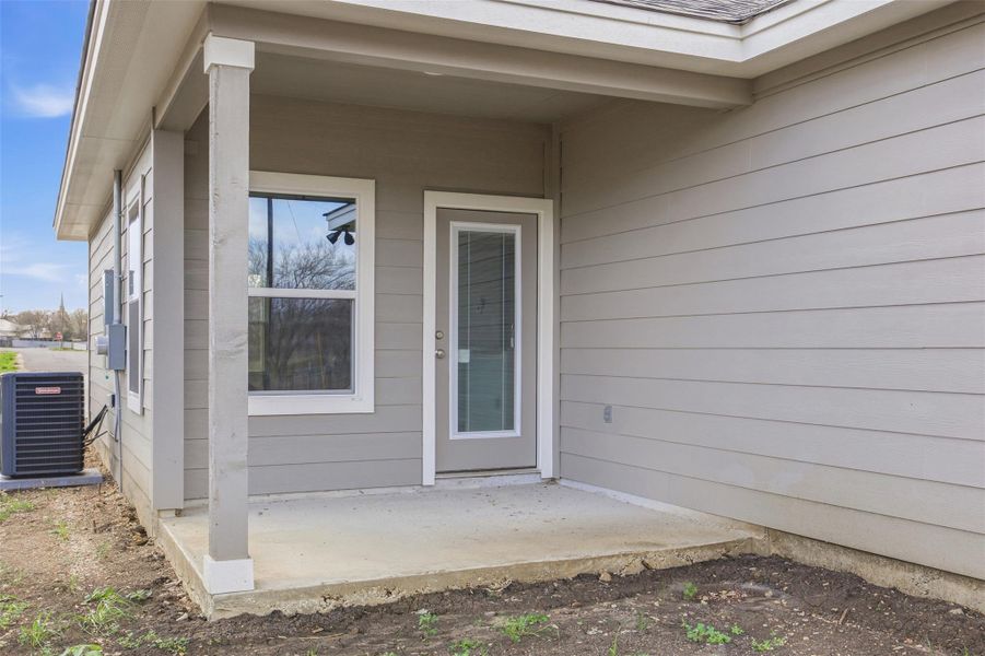 A welcoming rear entry with a small concrete patio offers an inviting outdoor space.