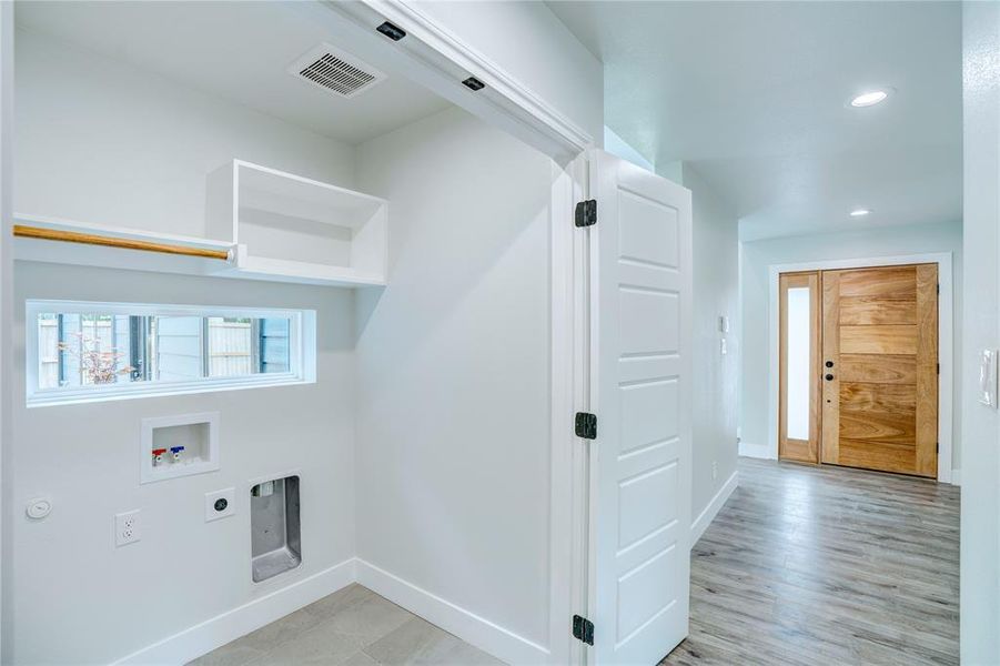 Laundry area featuring a built-in shelf, hanging rod, and a horizontal window