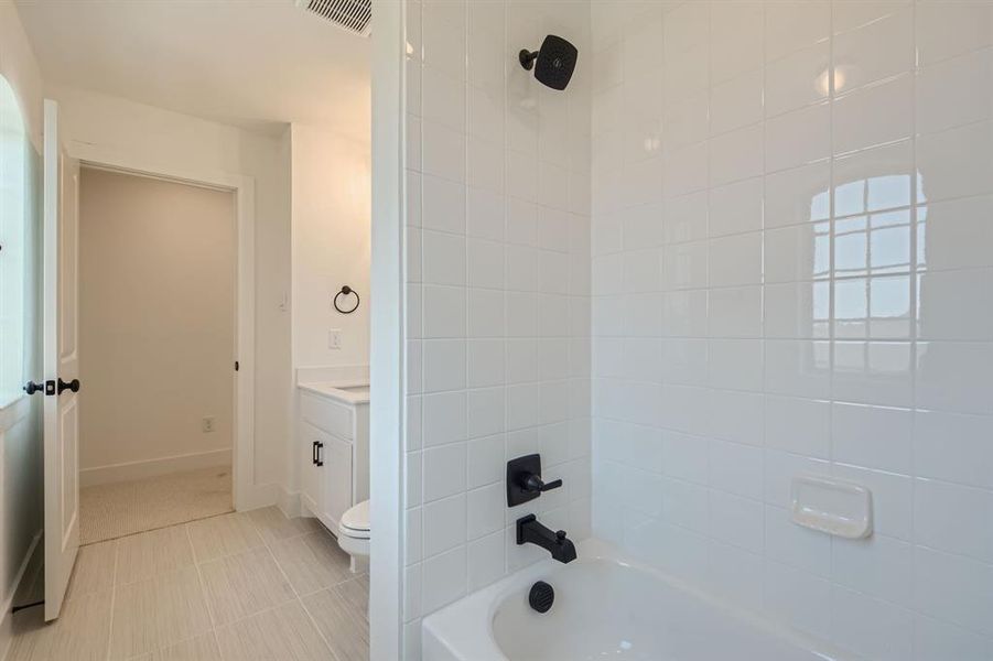 Full bathroom featuring tile patterned flooring, tiled shower / bath combo, vanity, and toilet