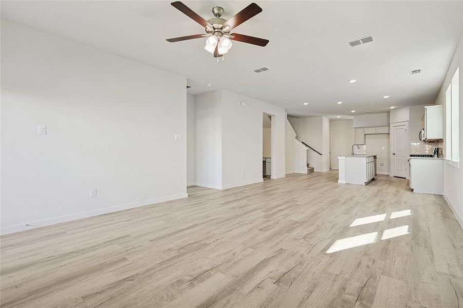 Unfurnished living room featuring ceiling fan and light wood-type flooring