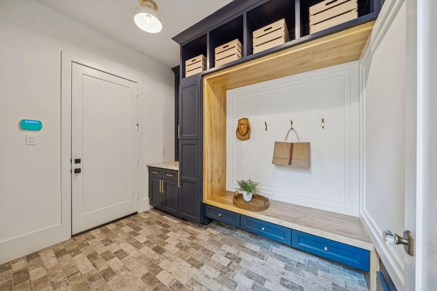 This is the mud room with brick flooring and built-in storage cabinets. The door leads to the garage.