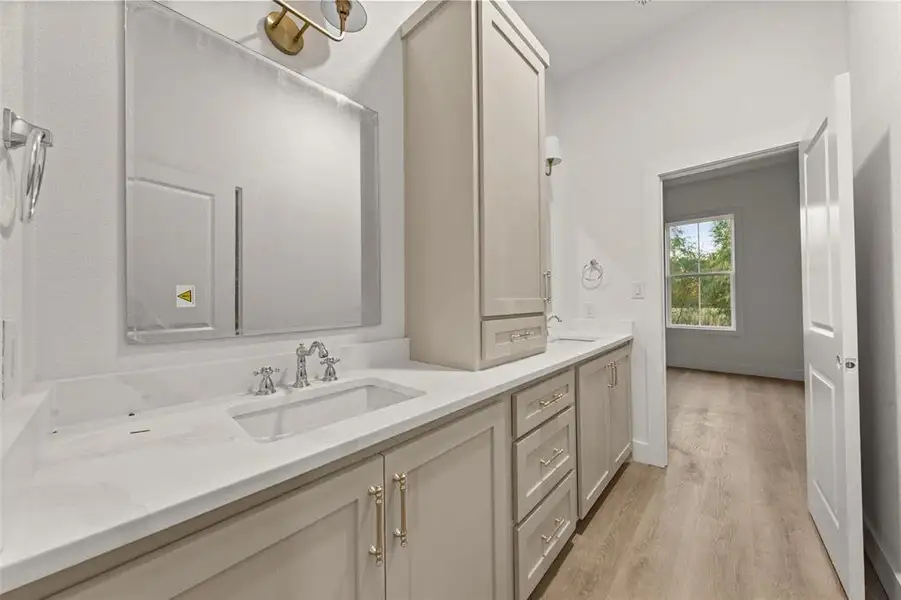 Full bath with double vanity and light wood-style flooring Full bath with double vanity and light wood-style flooring