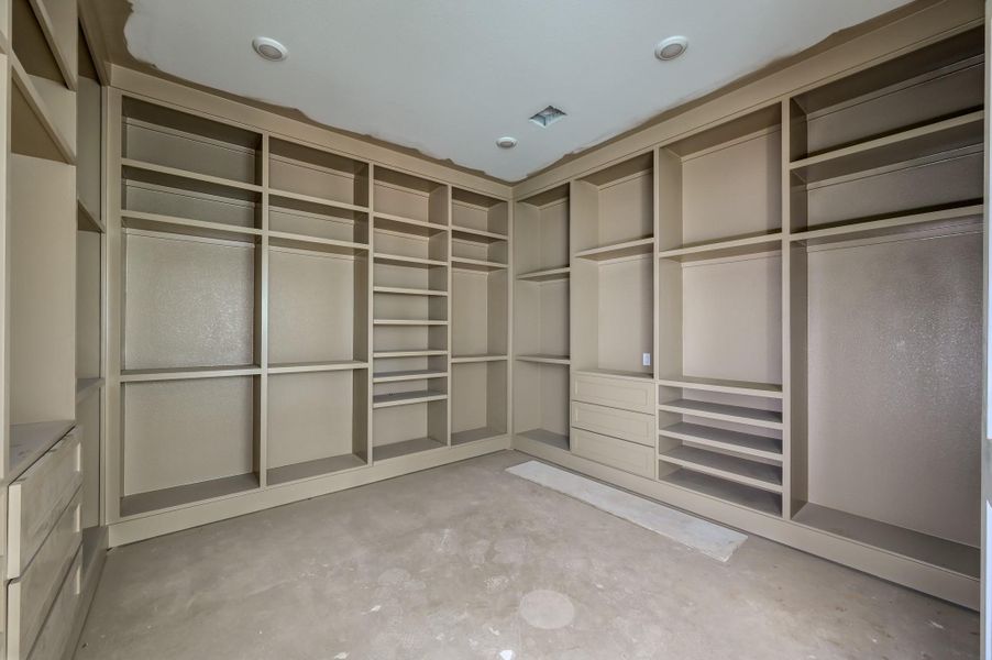 Spacious walk-in closet with custom built-in shelving and ample storage options, ideal for organizing clothing and accessories.