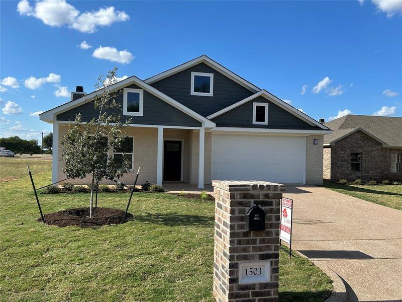 View of front of property featuring driveway, brick siding, and a front yard