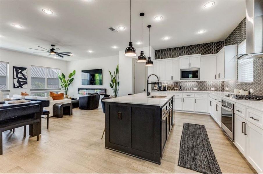 Kitchen featuring bright natural light, wall chimney range hood, white cabinetry, herringbone backsplash, and recessed and pendant lighting