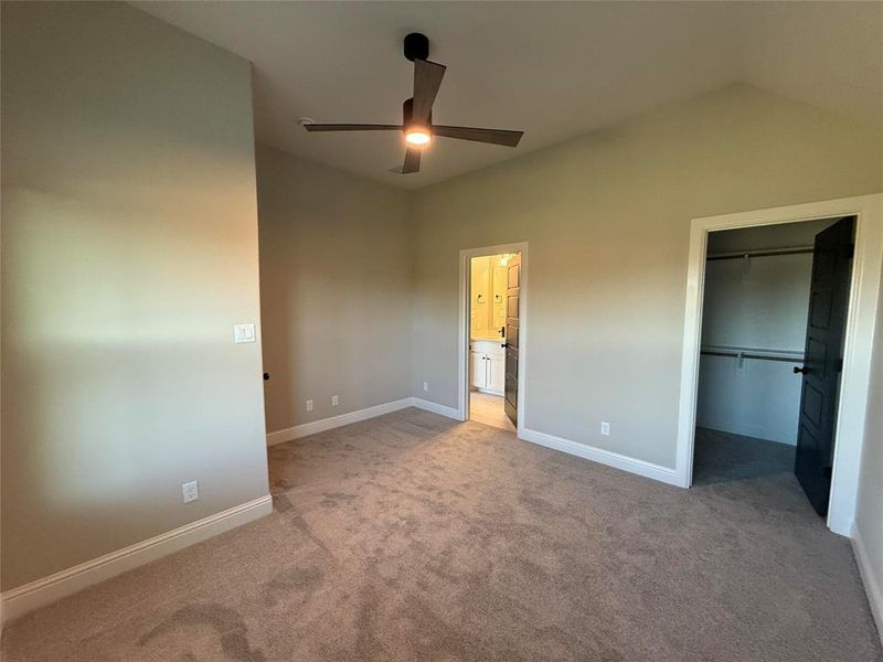 Unfurnished bedroom featuring a spacious closet, carpet floors, and ceiling fan Unfurnished bedroom featuring a spacious closet, carpet floors, and ceiling fan