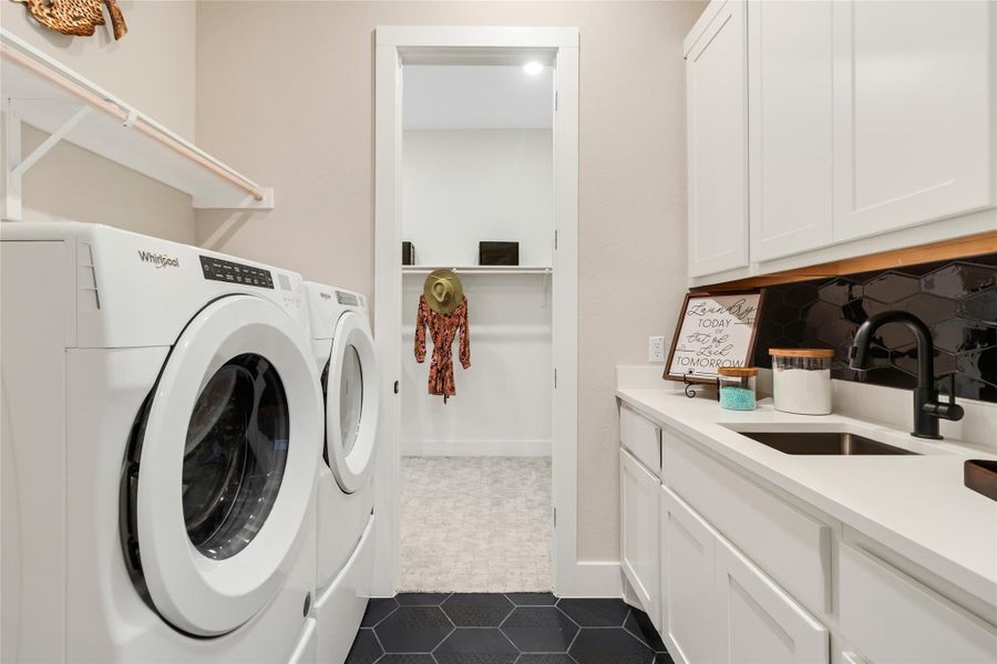 Washroom with washer and dryer, cabinet space, and dark tile patterned floors Washroom with washer and dryer, cabinet space, and dark tile patterned floors