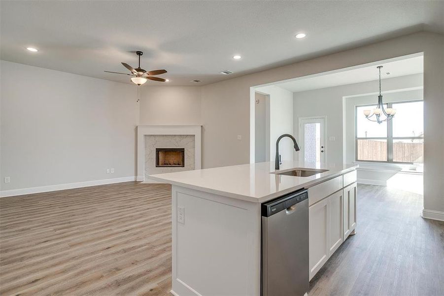 Kitchen with sink, dishwasher, light hardwood / wood-style flooring, a center island with sink, and white cabinets