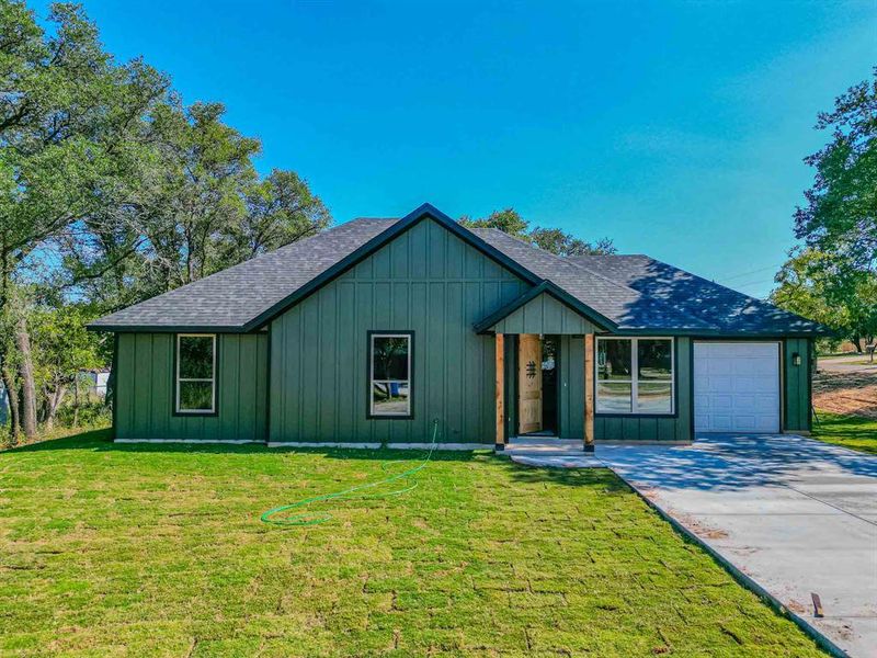 View of front of property with board and batten siding, roof with shingles, and driveway