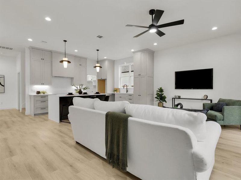 Living room with light wood-type flooring, ceiling fan, and sink