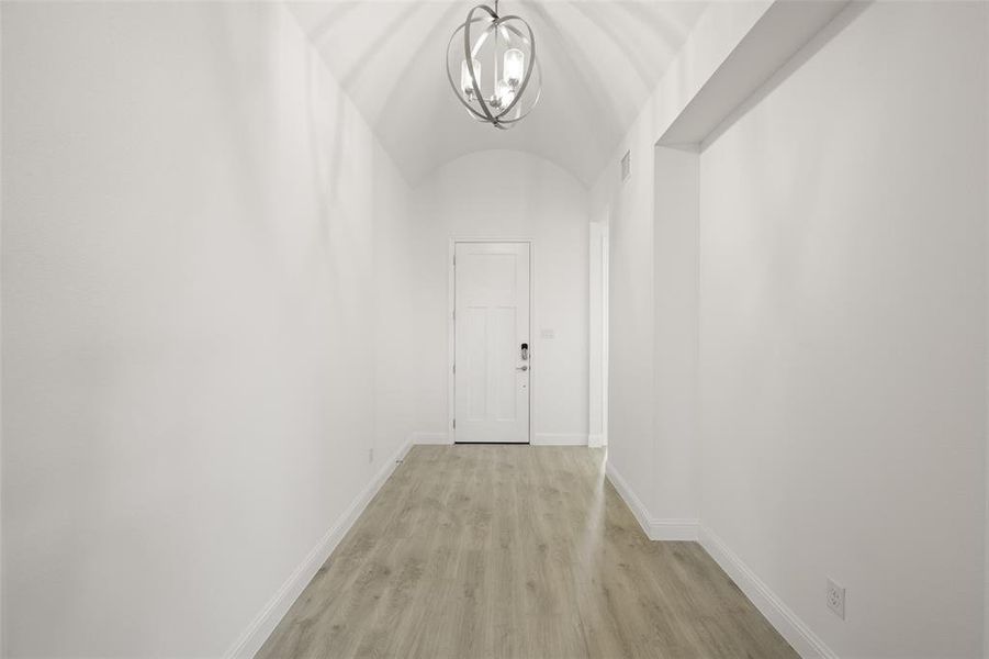 Hallway featuring a chandelier and light wood-type flooring Hallway featuring a chandelier and light wood-type flooring