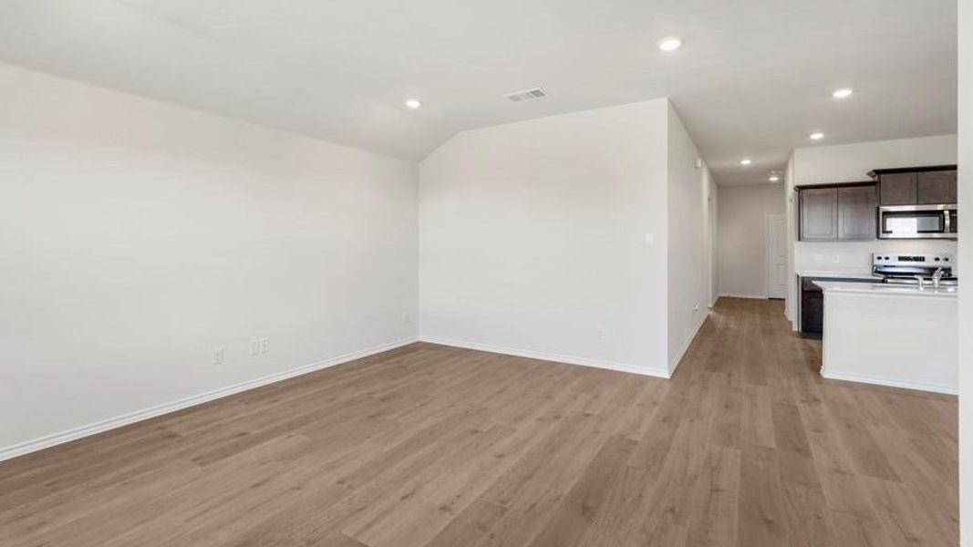 Spacious room featuring wood-finish flooring, recessed lighting, and a white baseboard trim