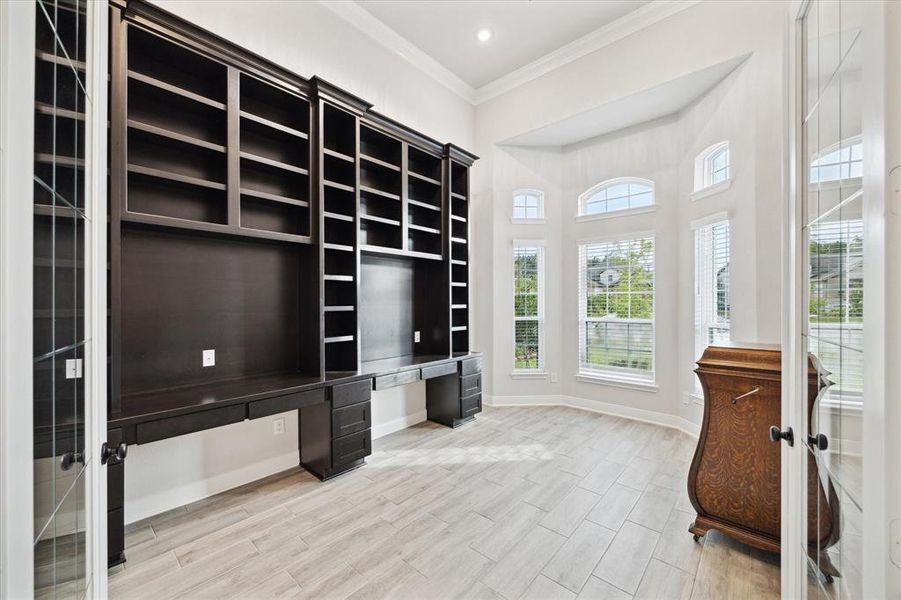 This large office at the front of the home has custom built double desks that feature beautiful book shelves above.