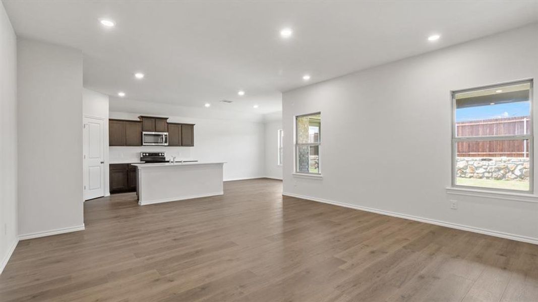 Open-concept living space featuring wood-finish flooring, recessed lighting, and white baseboards