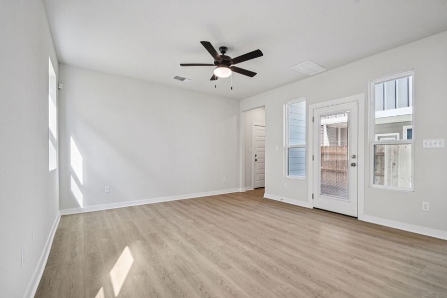 A room with a ceiling fan and a wood floor.