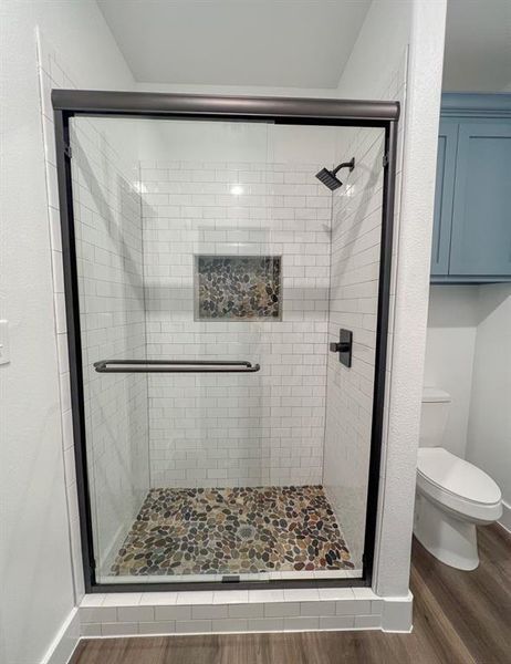 Bathroom featuring toilet, hardwood / wood-style flooring, and walk in shower