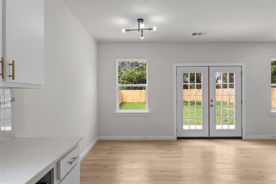 Open-concept interior featuring light wood-finish flooring, white walls, and a modern ceiling fixture