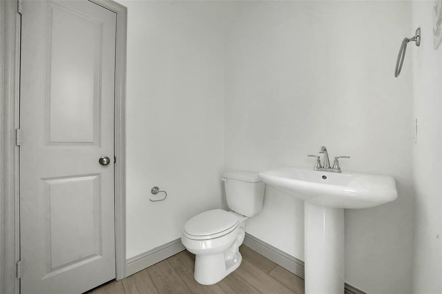 Half bathroom with toilet and light wood finished floors Half bathroom with toilet and light wood finished floors