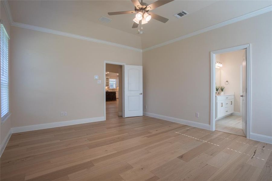 Unfurnished bedroom featuring connected bathroom, ornamental molding, light hardwood / wood-style floors, and ceiling fan