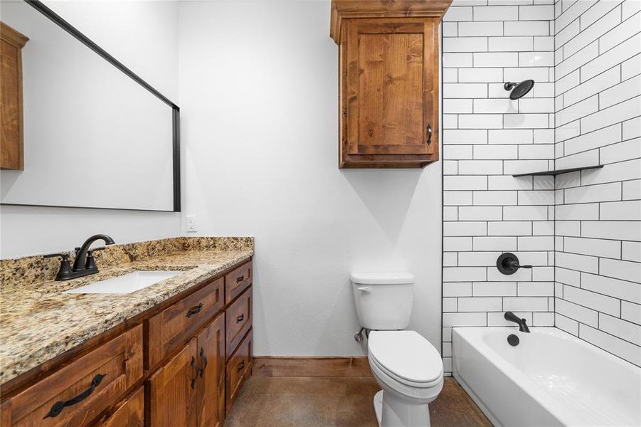 Full bathroom with toilet, vanity, shower / bath combination, and baseboards Full bathroom with toilet, vanity, shower / bath combination, and baseboards