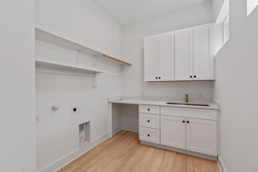 A well-appointed laundry area features practical shelving, cabinetry, and a utility sink for everyday convenience.
