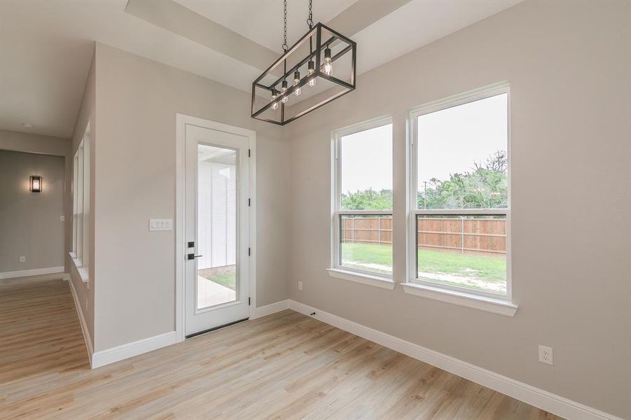 Unfurnished dining area with a chandelier, baseboards, and light wood-style floors Unfurnished dining area with a chandelier, baseboards, and light wood-style floors