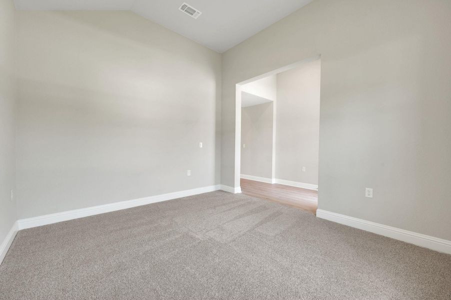 Carpeted spare room featuring lofted ceiling and baseboards Carpeted spare room featuring lofted ceiling and baseboards