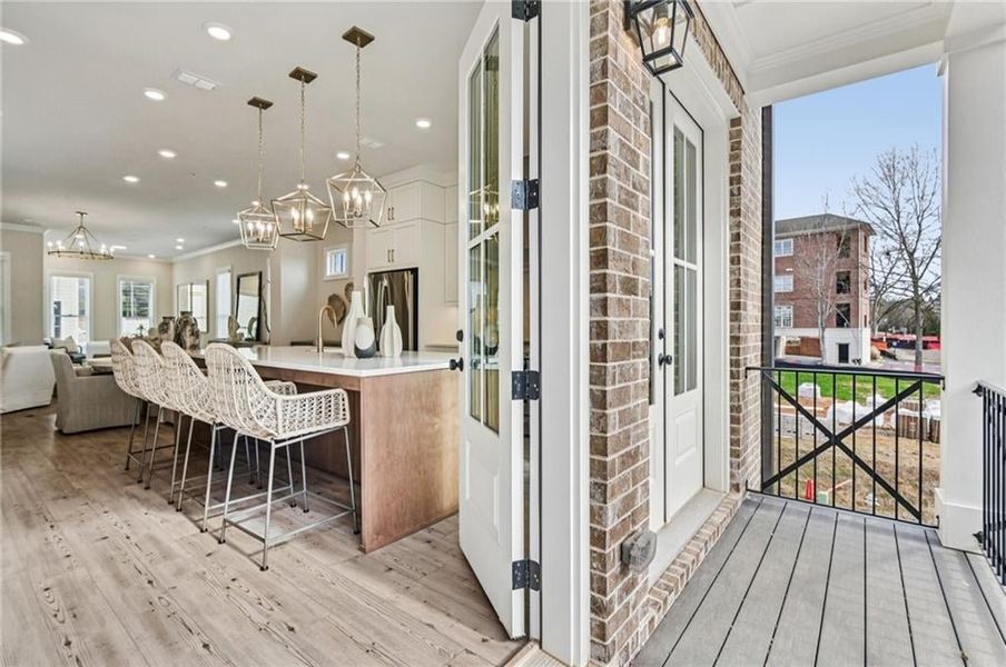 Kitchen with ornamental molding, open floor plan, white cabinetry, a large island, and a breakfast bar