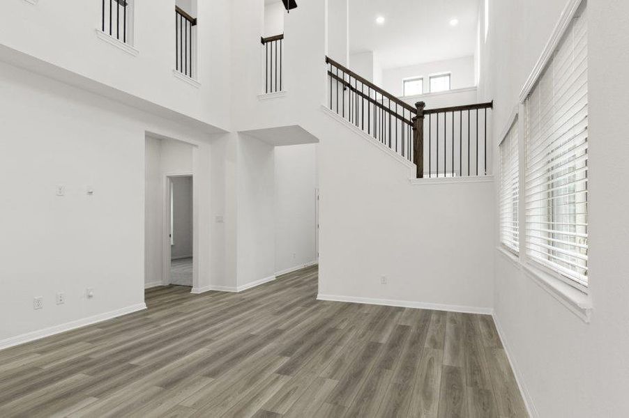 Unfurnished living room featuring wood finished floors and a high ceiling Unfurnished living room featuring wood finished floors and a high ceiling