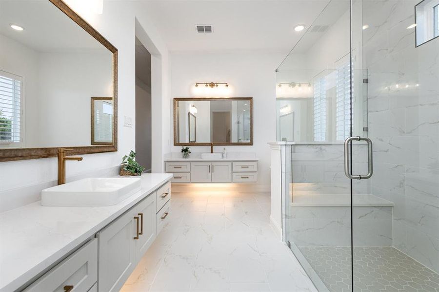 Full bathroom featuring two vanities, light marble finish flooring, a marble finish shower, and recessed lighting