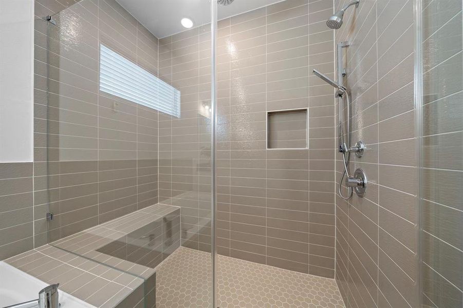 The glass shower is large enough for two people and has a convenient bench inside.