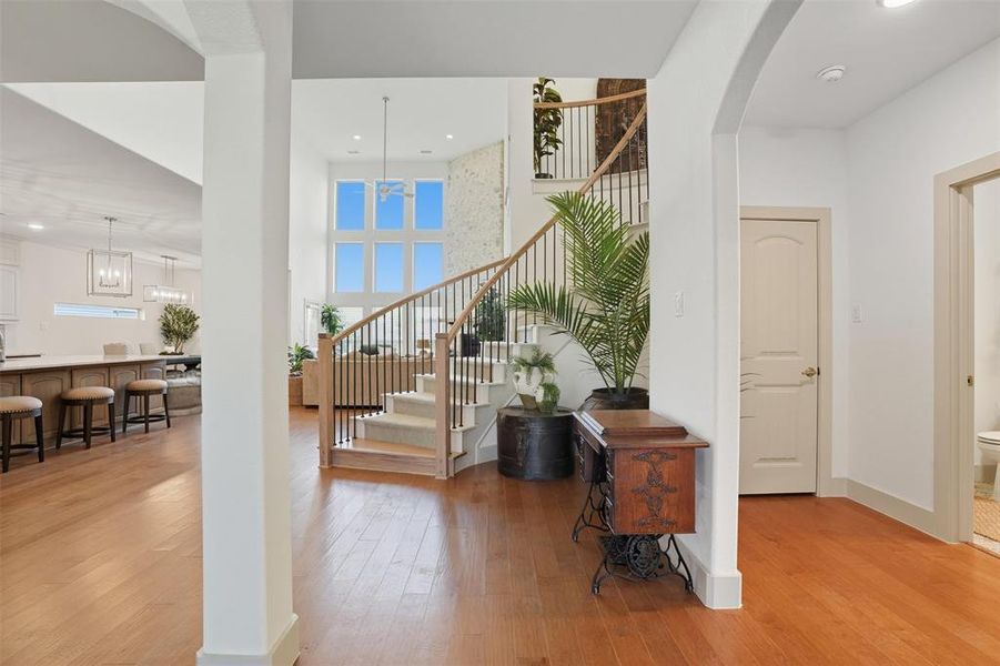Foyer entrance featuring light wood finished floors, stairs, a towering ceiling, arched walkways, and recessed lighting Foyer entrance featuring light wood finished floors, stairs, a towering ceiling, arched walkways, and recessed lighting