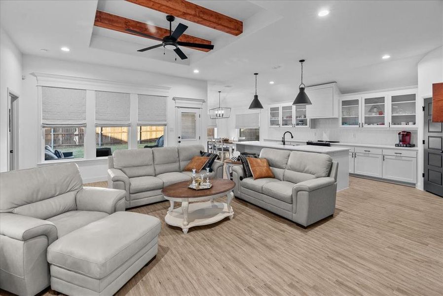 Living area with beamed ceiling, recessed lighting, light wood-style flooring, and ceiling fan