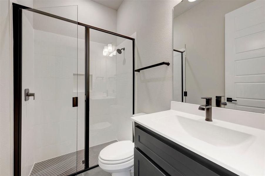 Contemporary bathroom featuring a glass-enclosed shower with matte black framing, white subway tile walls, and a hexagonal floor tile pattern