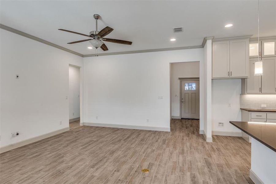 Unfurnished living room with crown molding, recessed lighting, light wood finished floors, and ceiling fan Unfurnished living room with crown molding, recessed lighting, light wood finished floors, and ceiling fan