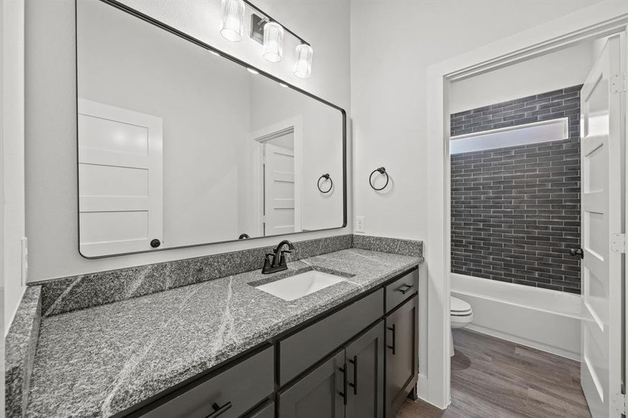 Full bathroom with vanity, dark wood-type flooring, and shower / bathtub combination