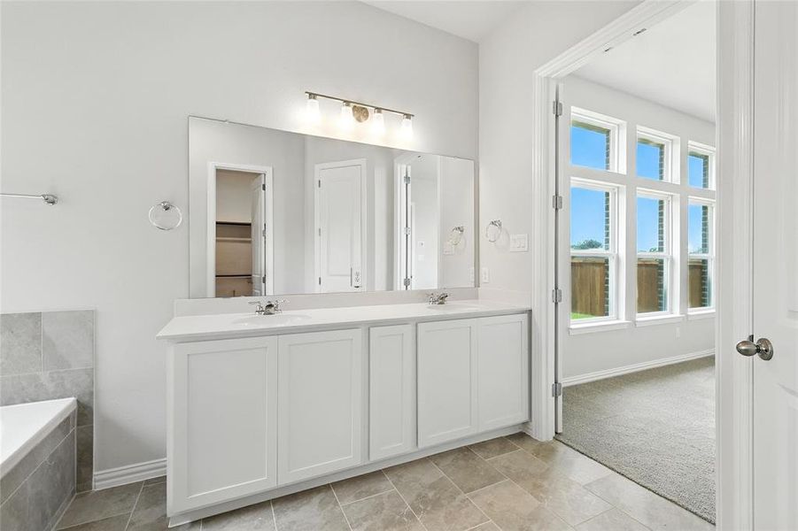 Bathroom with double vanity, light carpet, and a garden tub