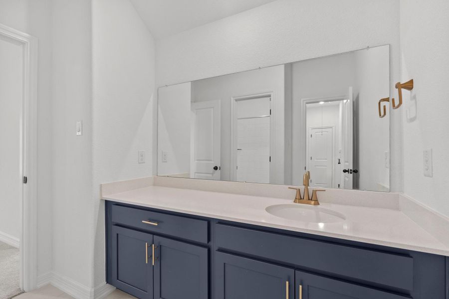 The secondary bath features tile flooring, custom stained cabinetry and light countertops and a shower/tub combo. Perfect for accommodating any visiting family and friends.