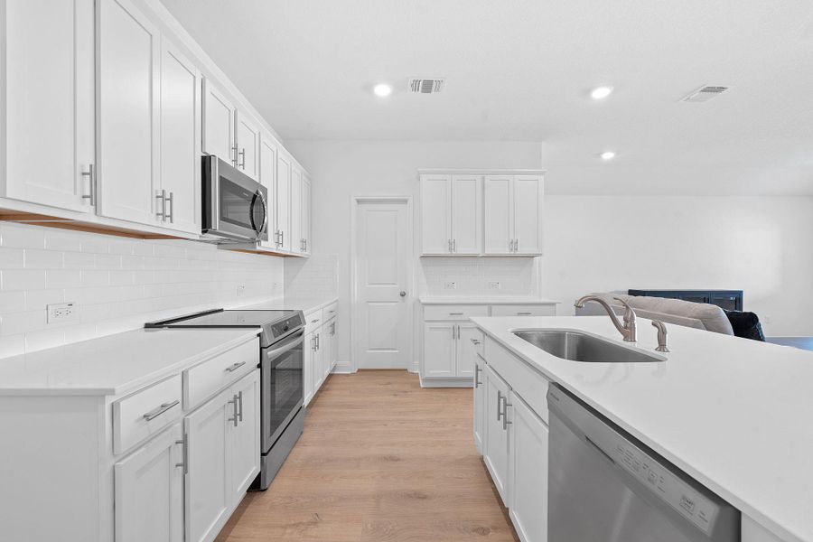 Kitchen featuring stainless steel appliances, white cabinets, backsplash, light wood-type flooring, and recessed lighting Kitchen featuring stainless steel appliances, white cabinets, backsplash, light wood-type flooring, and recessed lighting