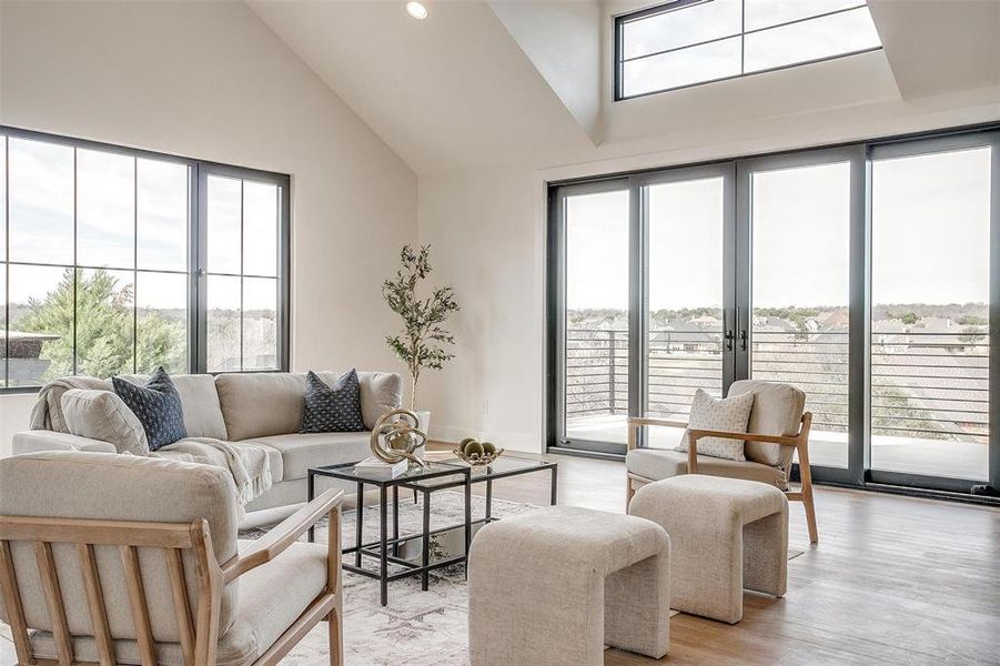 Living room with high vaulted ceiling, light wood-style floors, recessed lighting, and french doors